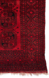 Detalle del borde y la esquina inferior de una alfombra oriental roja.