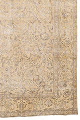 Detalle del borde inferior derecho de la alfombra mostrando el diseño floral en tonos neutros y contorno envejecido.