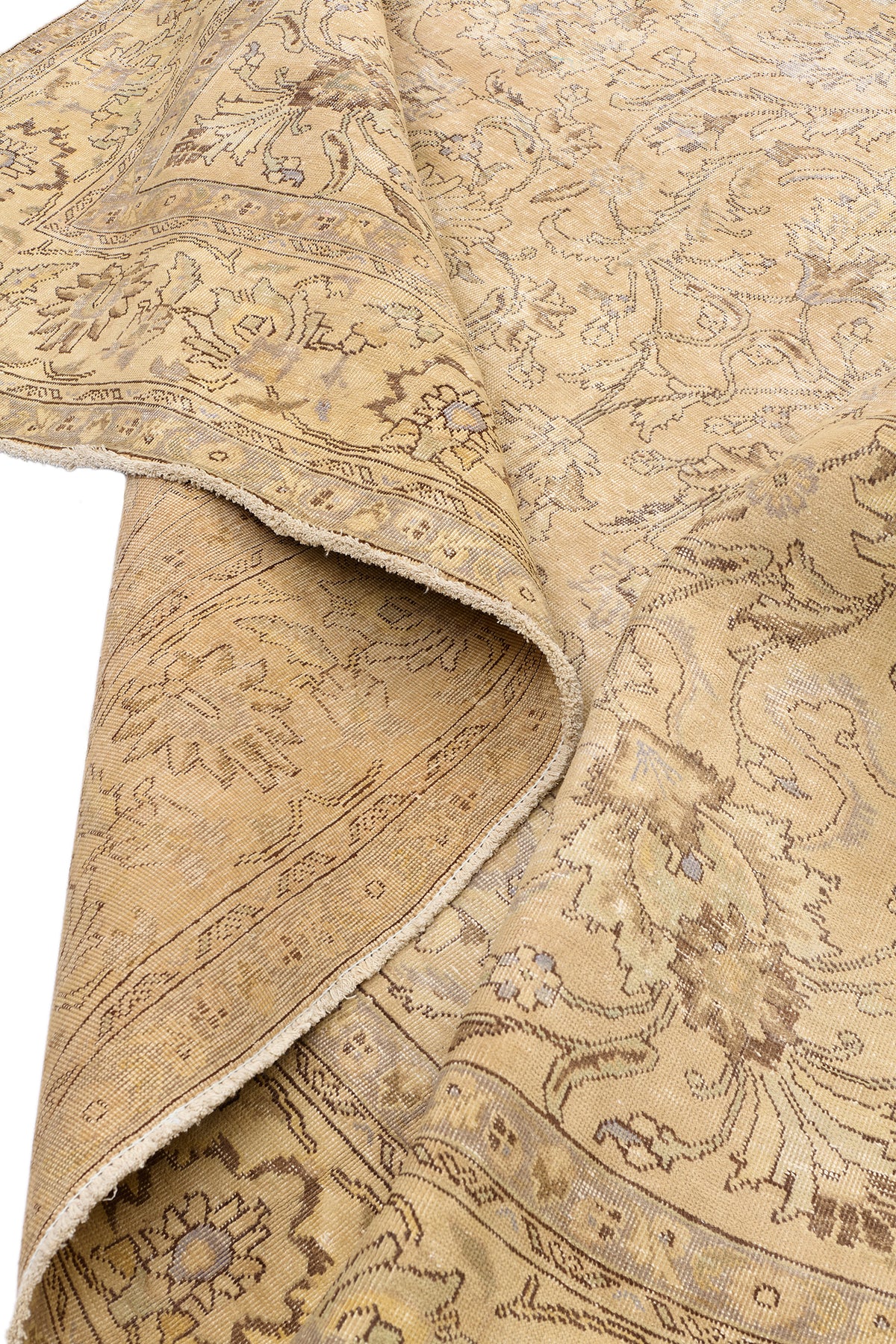 Vista del reverso de la alfombra doblada, destacando la calidad del tejido y los colores suaves del anverso.