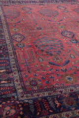 Esquina de la alfombra persa con un patrón de flores detallado y borde enmarcado en azul oscuro.