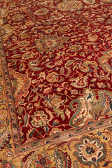 Esquina de alfombra persa con detalles de flores y hojas, enmarcada por un borde decorado en beige y rojo.
