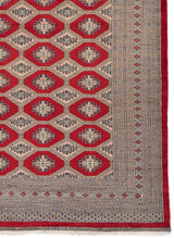 Detalle de los patrones geométricos de la alfombra, con tonos rojos y beige.
