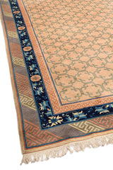Esquina de alfombra oriental con patrones geométricos y borde decorado en azul y rosa.