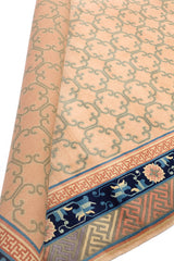 Detalle de alfombra oriental beige enrollada, mostrando su fino diseño de bordes y patrones geométricos.