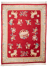 Alfombra de fondo rojo con motivos orientales y dragones en relieve, enmarcada por bordes ornamentados en tonos beige y verde.