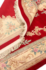Parte doblada de la alfombra roja mostrando los detalles del tejido y diseño floral.