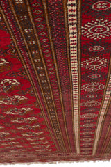 Vista de esquina de alfombra oriental con detalles intrincados de figuras y franjas decorativas.