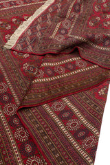 Alfombra oriental enrollada, mostrando textura y detalles del patrón geométrico.