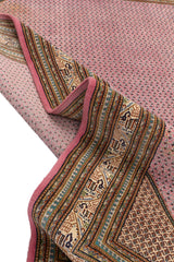 Alfombra rosada doblada, mostrando detalles de sus bordes geométricos decorativos.