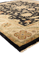 Vista lateral de una alfombra con decoración floral en tonos oscuros y bordes beige.