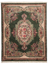Vista frontal de alfombra verde con detalles florales enmarcados en beige y rosa.