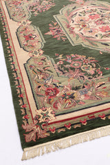 Vista diagonal de la alfombra verde resaltando su diseño floral y borde beige con detalles rosados.