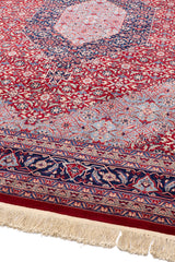 Vista lateral de la alfombra oriental destacando el diseño simétrico en rojo y azul y el borde detallado.