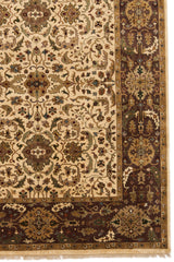 Detalle del borde y patrón floral en alfombra oriental en tonos marrón oscuro y beige.