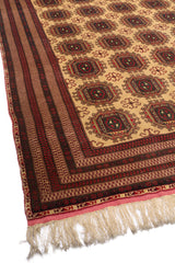 Vista lateral de la alfombra resaltando los patrones simétricos y el diseño en tonos beige y rojo.