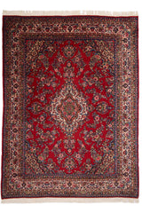 Alfombra persa con un diseño floral intrincado en tonos rojos y detalles en azul y beige.