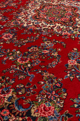Vista cercana de los motivos florales coloridos en la alfombra roja, resaltando sus tonos vibrantes.
