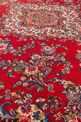 Vista de perfil que muestra los patrones florales intrincados de la alfombra sobre el fondo rojo brillante.