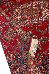 Bordes de la alfombra persa roja con una vista doblada, exhibiendo su reverso y los detalles del tejido.