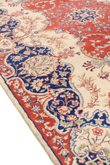 Vista cercana del patrón floral central de la alfombra con detalles en beige, azul y rojo.