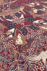 Alfombra artesanal con patrones florales y humanos bordados en colores cálidos.