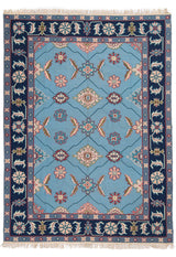 Alfombra con fondo azul claro y borde decorado con flores geométricas.