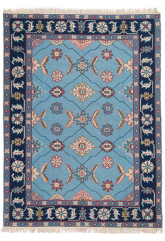 Alfombra con fondo azul claro y borde decorado con flores geométricas.
