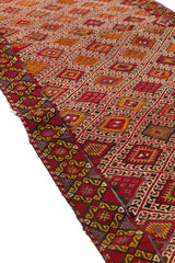 Vista lateral de alfombra kilim mostrando el contraste entre sus patrones geométricos en el centro y los bordes decorados