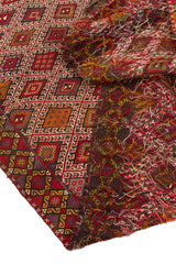 Detalle de la esquina de una alfombra kilim mostrando los flecos y los patrones geométricos triangulares en sus bordes coloridos.