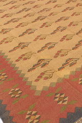 Vista inclinada de la alfombra kilim mostrando el diseño central y los bordes geométricos en tonos suaves de amarillo y verde.