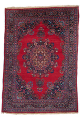 Alfombra persa clásica de fondo rojo con un medallón floral central y detalles azul oscuro en el borde.