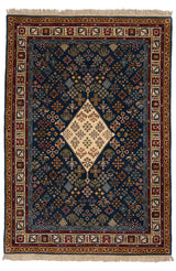 Vista completa de alfombra persa con un fondo rojo y detalles en azul oscuro, con un patrón floral central y borde elaborado.