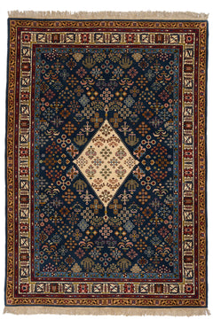 Vista completa de alfombra persa con un fondo rojo y detalles en azul oscuro, con un patrón floral central y borde elaborado.