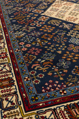 Vista en ángulo de la alfombra persa mostrando el patrón geométrico con detalles florales sobre fondo rojo y borde oscuro.