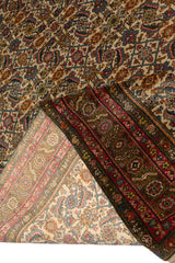 Alfombra oriental con motivos geométricos y florales sobre un fondo beige y marrón.