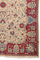 Detalle de una esquina de alfombra persa con fondo beige y bordes decorados en azul y rojo.