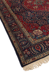 Alfombra oriental clásica con fondo rojo intenso y detalles florales en verde y beige, con flecos en los extremos