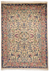 Alfombra de tonos beige con intrincado diseño floral y detalles en rosa y azul, marco en tonos oscuros