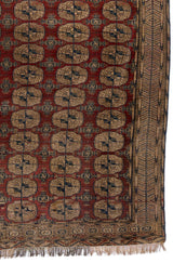 Vista de cerca de una alfombra oriental con figuras geométricas repetitivas y un borde detallado en tonos beige y azul.