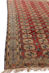 Perspectiva lateral de una alfombra oriental con fondo rojo y un borde beige con detalles intrincados.