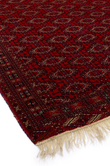 Vista lateral de una alfombra roja que destaca su textura y detalles geométricos.