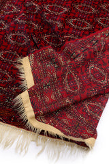Detalle del reverso de una alfombra roja, mostrando la calidad del tejido y el borde decorado.