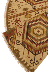 Detalle del borde y los flequillos de la alfombra beige circular con patrones tradicionales florales y geométricos.