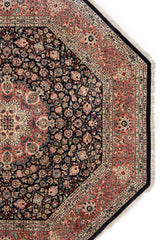 Detalle de una alfombra persa octagonal mostrando el intrincado patrón floral en colores oscuros.