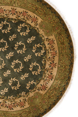 Detalle de bordes florales en alfombra verde oscuro con borde beige.