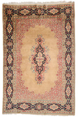 Vista completa de una alfombra oriental con patrón central en tonos beige y rojo, con bordes florales en negro y detalles azulados.