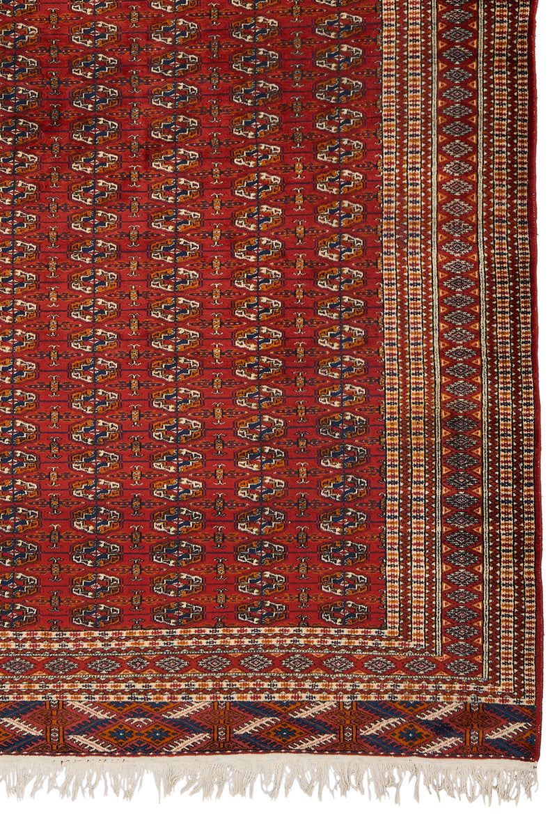 Detalle inferior derecho de la alfombra, mostrando el patrón geométrico y las franjas decorativas multicolores.