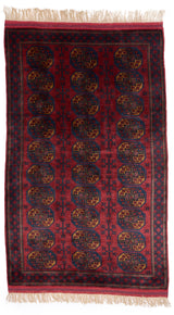 Alfombra turcomana con patrones geométricos en tonos rojos y azules.