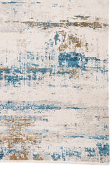 Detalle del diseño abstracto en tonos azul vibrante y beige sobre fondo marfil de la alfombra.