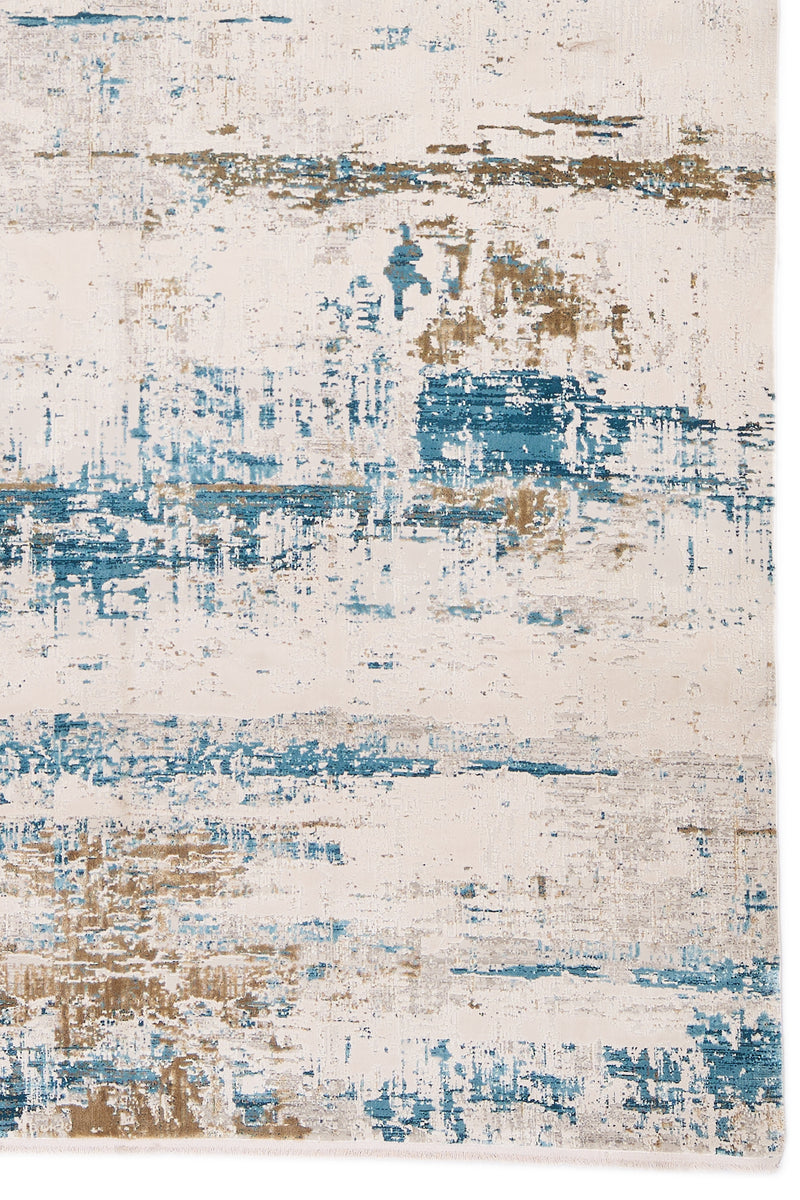 Detalle del diseño abstracto en tonos azul vibrante y beige sobre fondo marfil de la alfombra.